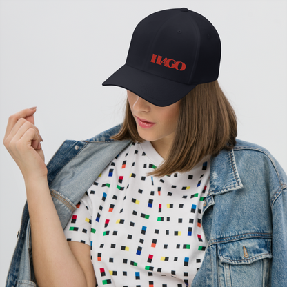 Person wearing a black cap with 'HAGO' logo, colorful patterned shirt, and denim jacket on a white background